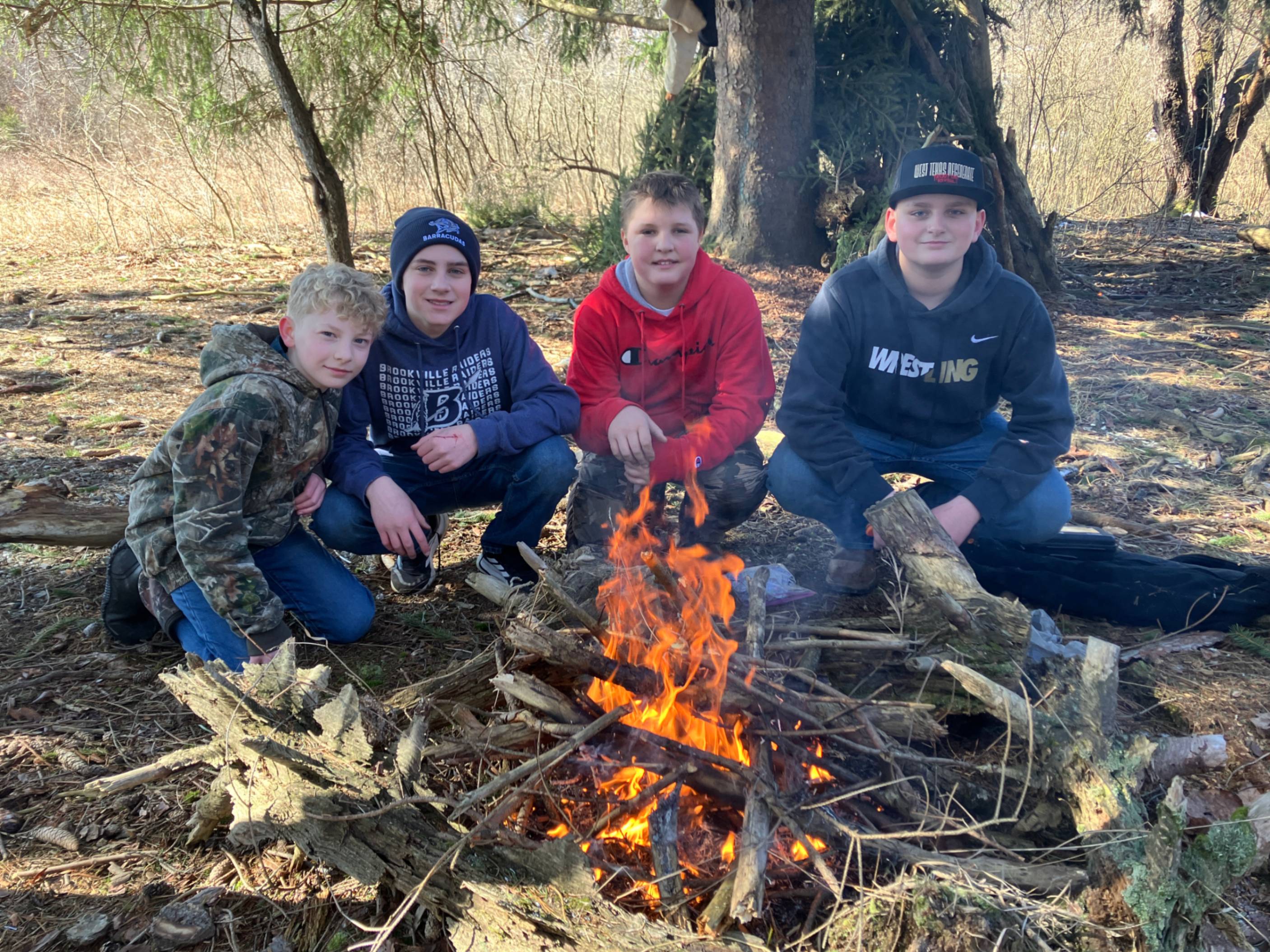 Ethan Werner, Holt Emery, Sawyer Lewis and Noah Kniseley sit by a camp fire they built.